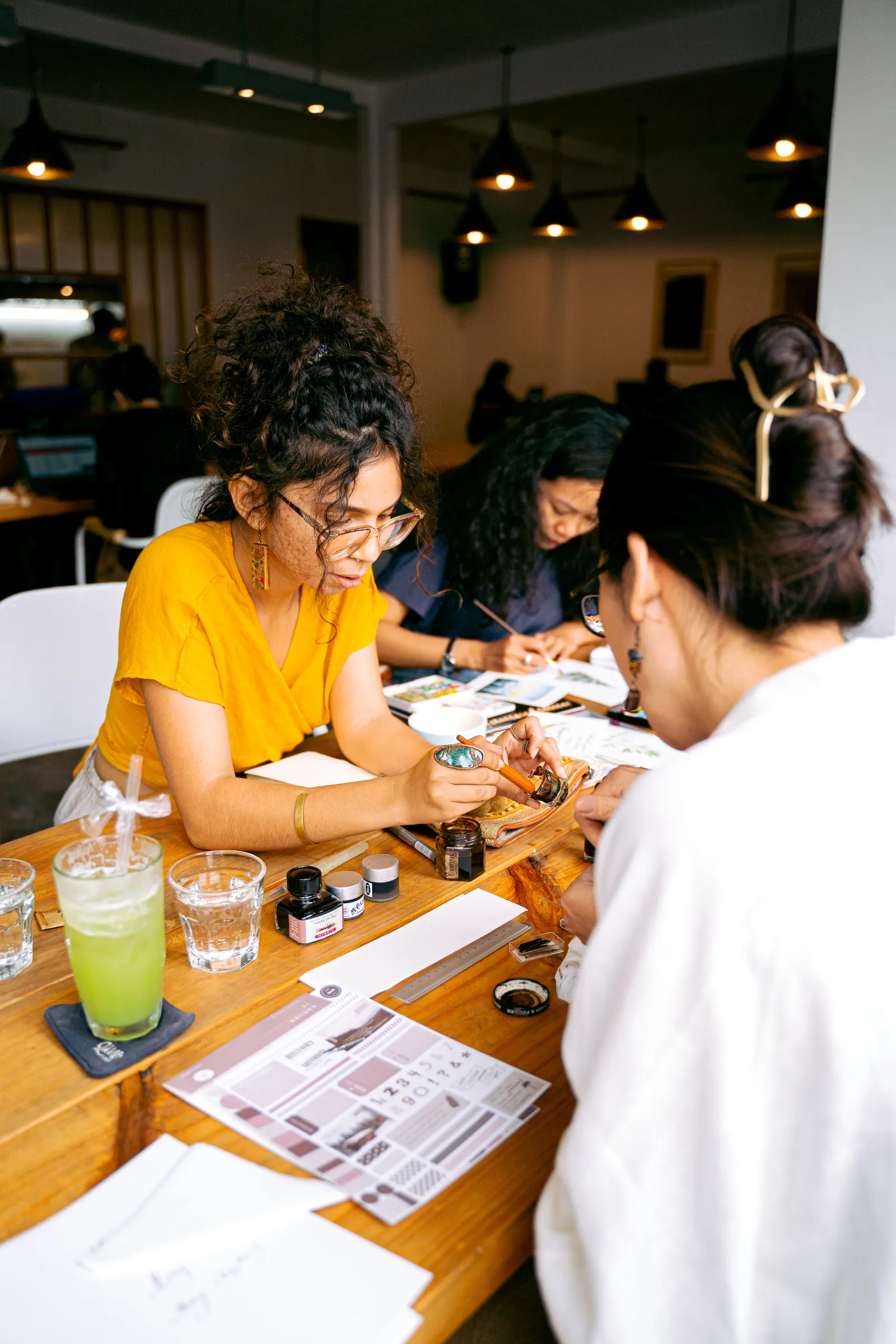 Vrouwen werken met papier, inkt en penselen tijdens een creatieve activiteit