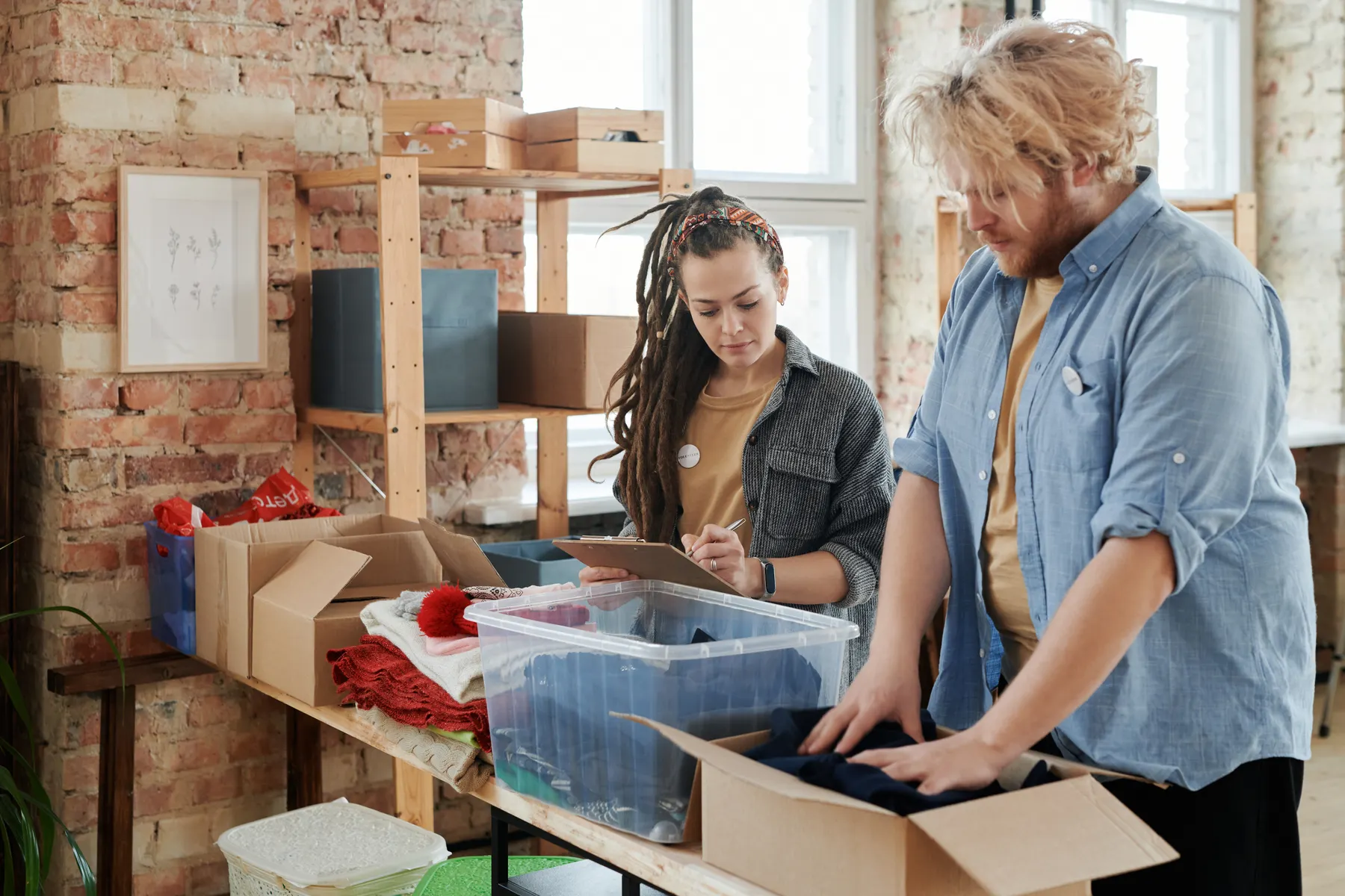 Twee vrijwilligers sorteren gedoneerde kleding aan een grote tafel